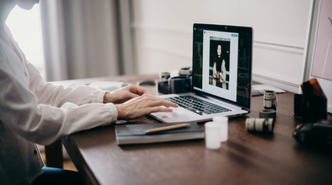 Woman Sitting At A Desk And Editing A Photograph On A Laptop